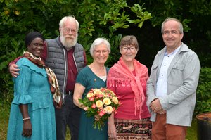 Eine Gruppe von Menschen steht draußen im Grünen. 