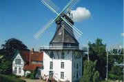 Weißes Gebäude mit schwarzem dach und Mühlarmen in türkis