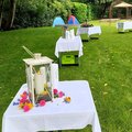 Weiß gedeckte Tische mit Taufkerzen im Freien