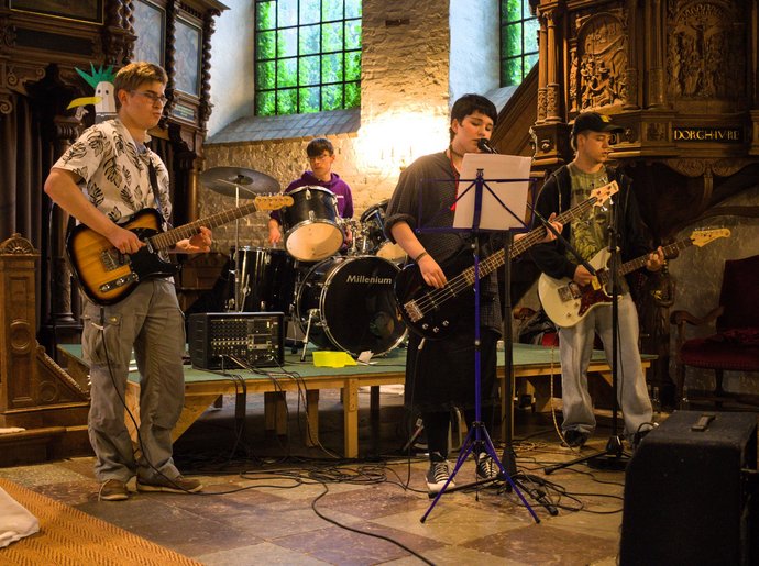 Vier Jugendliche mit Musikinstrumenten in einer Kirche