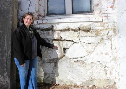 Pastorin Diana Krückmann vor dem Mauerwerk der Kirche mit Rissen
