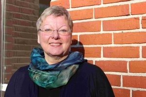 Die Referentin steht vor einer gemauerten Wand.