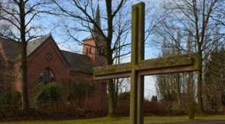 Im Hintergrund die Fockbeker Kirche, vorne ein Grabkreuz