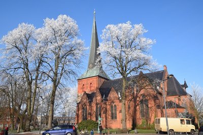 Nortorfer Kirche hinter winterlich-weißen Bäumen im Sonnenschein