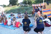 Eine Gruppe Menschen hockt und sitzt vor einem Strandkorb