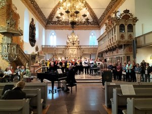 Blick in den mit Menschen gefüllten Altarraum einer Kirche