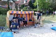 Fünf Menschen in gleichen Shirts sitzen im und um einen Strandkorb
