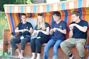 Vier Menschen im Strandkorb bewegen die Hände gleich