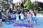 Kinder und Erwachsene stehen im Kreis am Strand