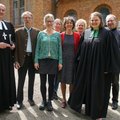 Acht Menschen im Sonnenschein vor einer Kirche