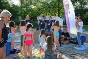 Eine Gruppe Kinder steht vor einem Strandkorb, in dem zwei Menschen sitzen
