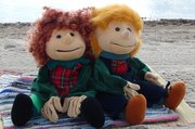 Zwei Handpuppen sitzen am Strand