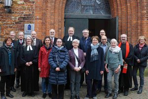 Eine Gruppe von Menschen steht vor einer Kirchentür.