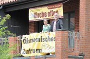 Zwei Menschen auf einem Balkon, Banner mit der Aufschrift "Ökumenisches Zentrum"